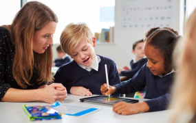Teacher with two young students looking at a tablet.