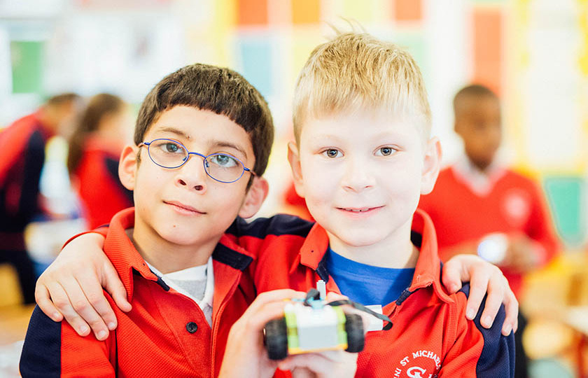 Two boys embracing and showing their lego creation.